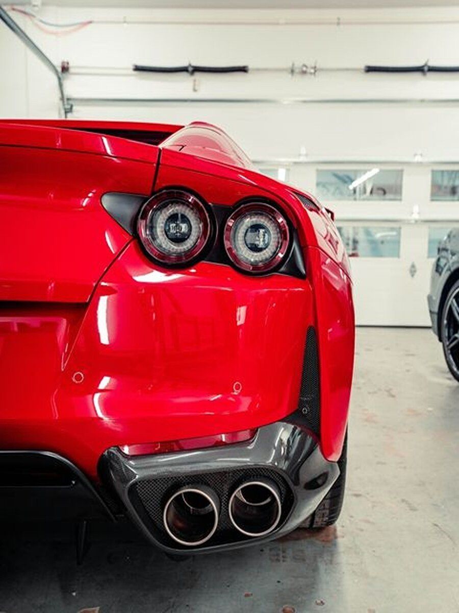 a red sports car is parked in a garage next to a black car .