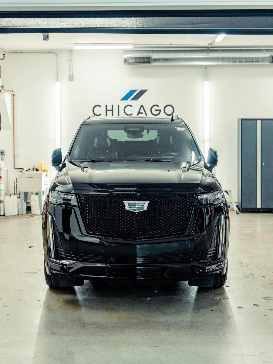 A black car is parked in a garage with the word chicago on the wall behind it.