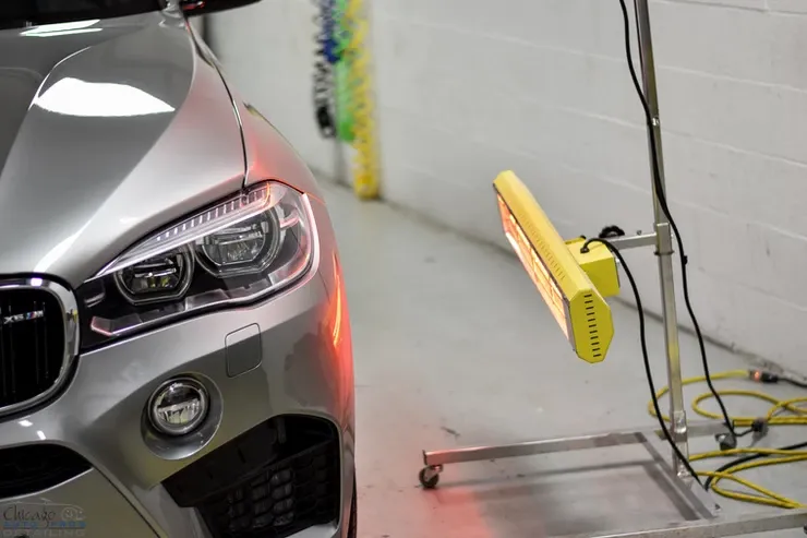 A car is sitting next to a yellow light in a garage.