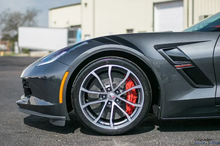 A black sports car with red brake calipers is parked in front of a building.