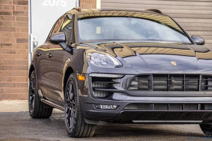 A black porsche macan is parked in front of a brick building.