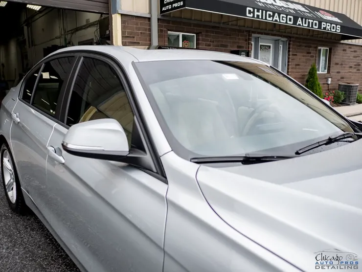 A silver car is parked in front of a building that says chicago auto pros