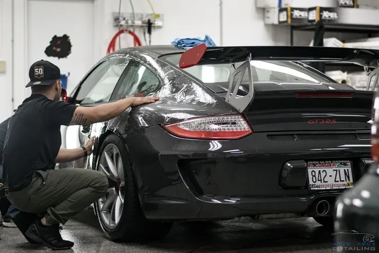 A man is wrapping a car in plastic in a garage.