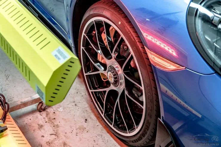 A blue car is sitting next to a yellow machine.