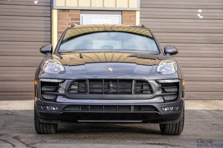 A black porsche macan is parked in front of a garage door.
