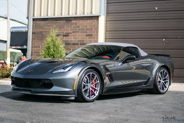 A gray corvette convertible is parked in front of a brick building.
