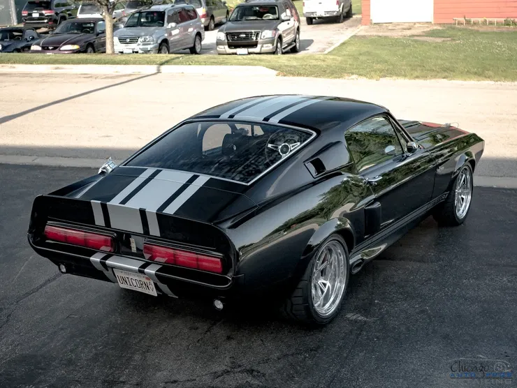 A black mustang with white stripes is parked in a parking lot