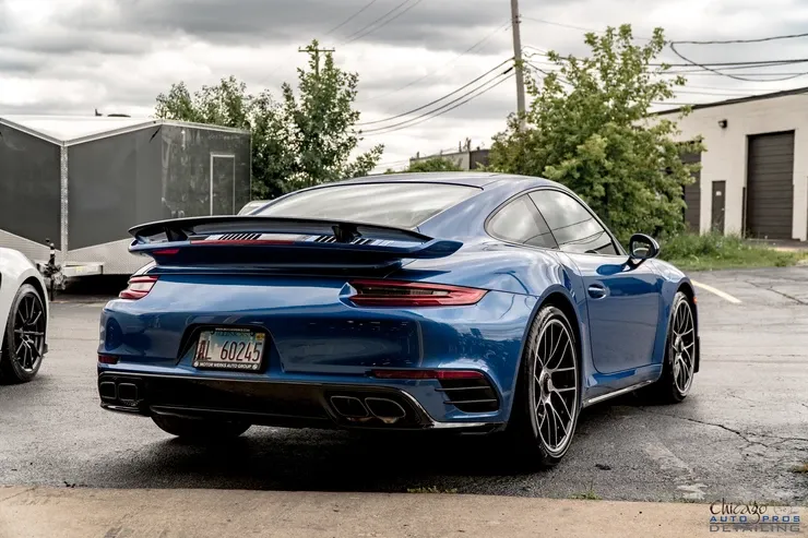 A blue porsche 911 turbo s is parked in a parking lot.