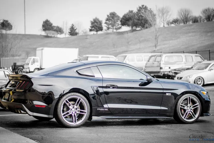 A black ford mustang is parked in a parking lot.