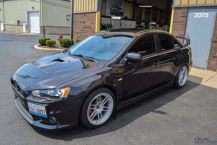 A black car is parked in front of a building with the number 2075 on it.