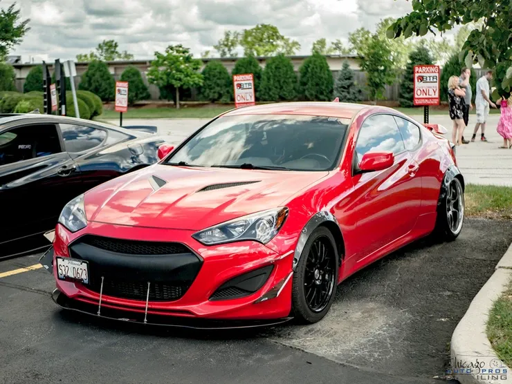 A red hyundai genesis is parked in a parking lot.