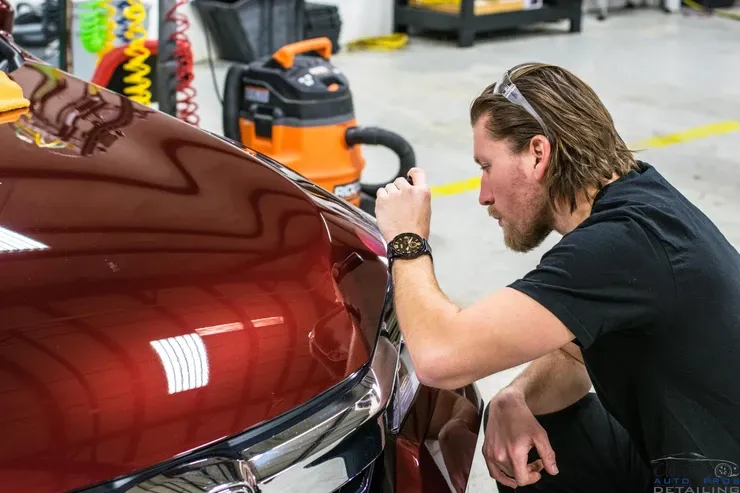 A man is working on a red car in a garage.