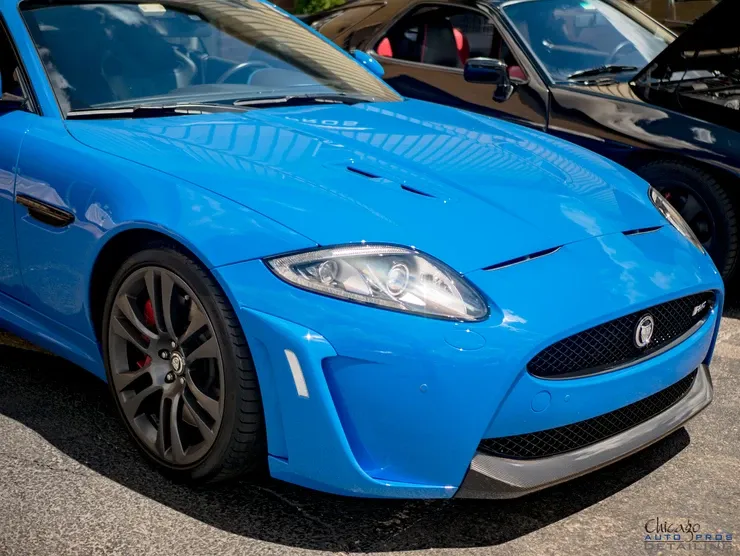 A blue jaguar is parked next to a black car