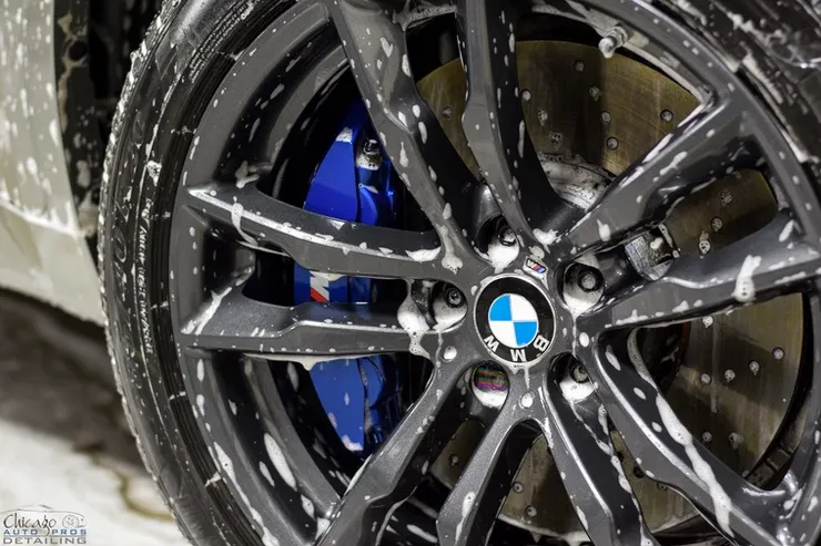 A close up of a bmw wheel with soap on it.