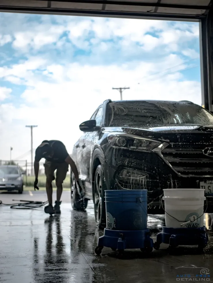 A man is washing a car in a garage.