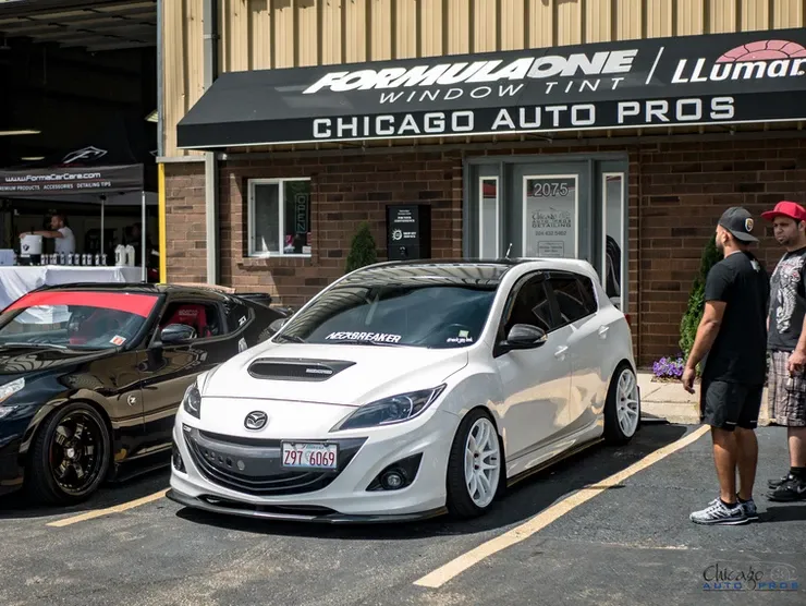 A white car is parked in front of a chicago auto pros store.