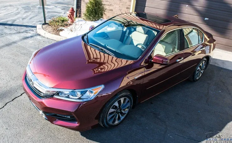 A red honda accord is parked in front of a garage.