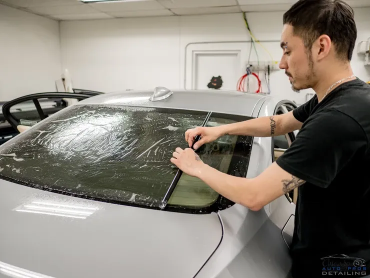 A man is putting a film on the windshield of a car.