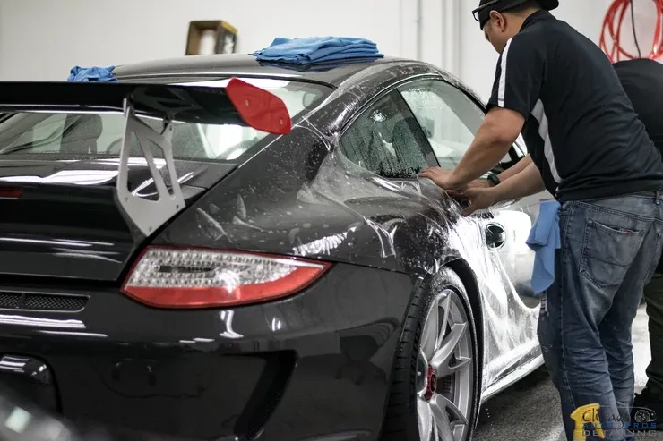 Two men are working on a black sports car in a garage.