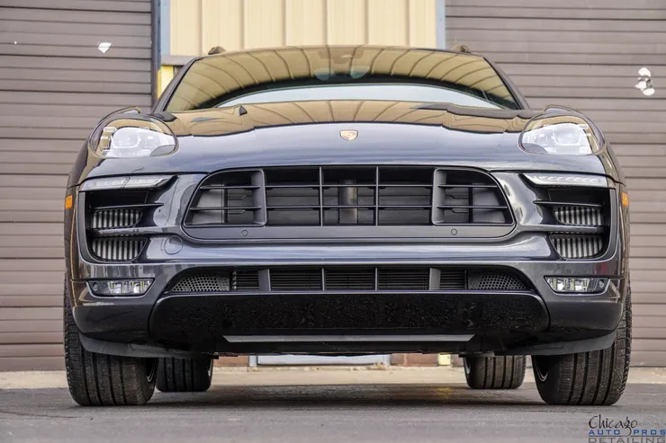 A black porsche macan turbo is parked in front of a building.