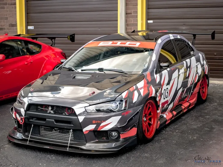 A mitsubishi lancer evo is parked in front of a garage