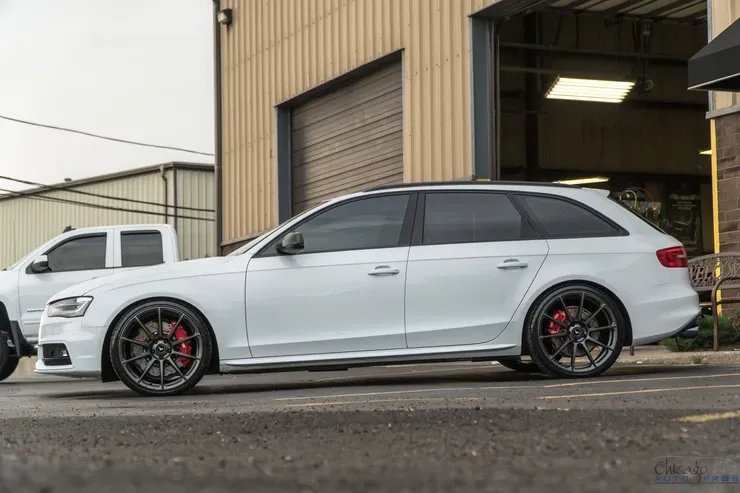 A white audi a4 is parked in front of a garage.