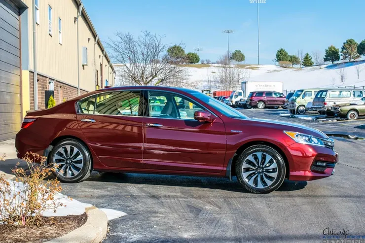 A red honda accord hybrid is parked in a parking lot.