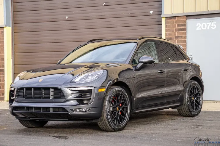 A black porsche macan turbo is parked in front of a garage door.