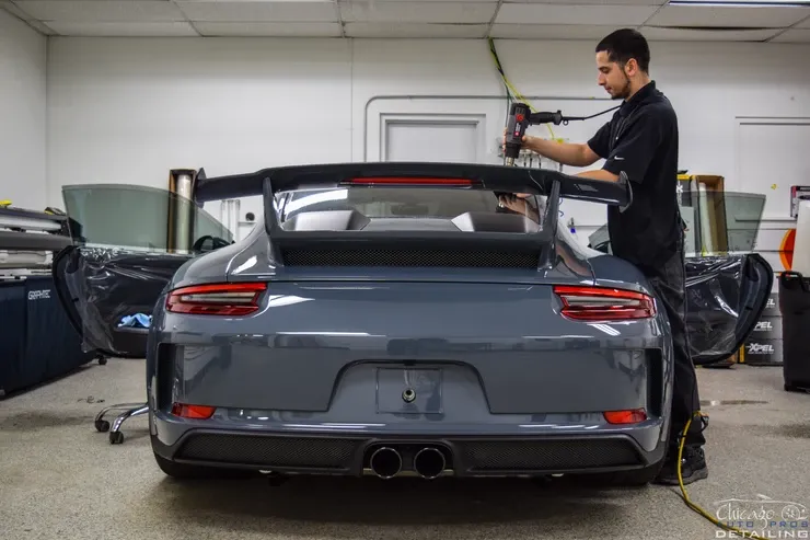 A man is working on a porsche 911 gt3 in a garage.