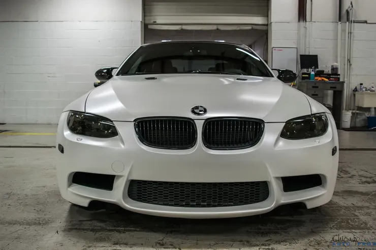 A white bmw m3 is parked in a garage.