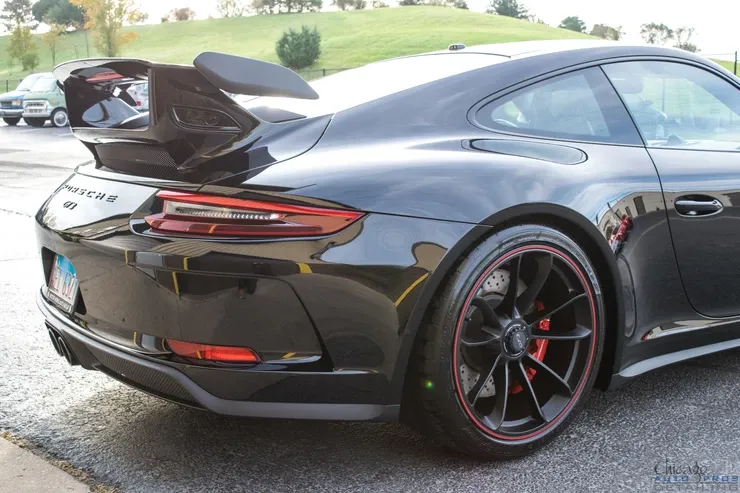 A black porsche 911 gt3 is parked on the side of the road