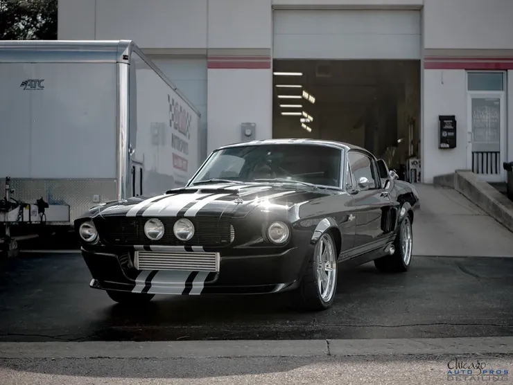 A black mustang is parked in front of a building