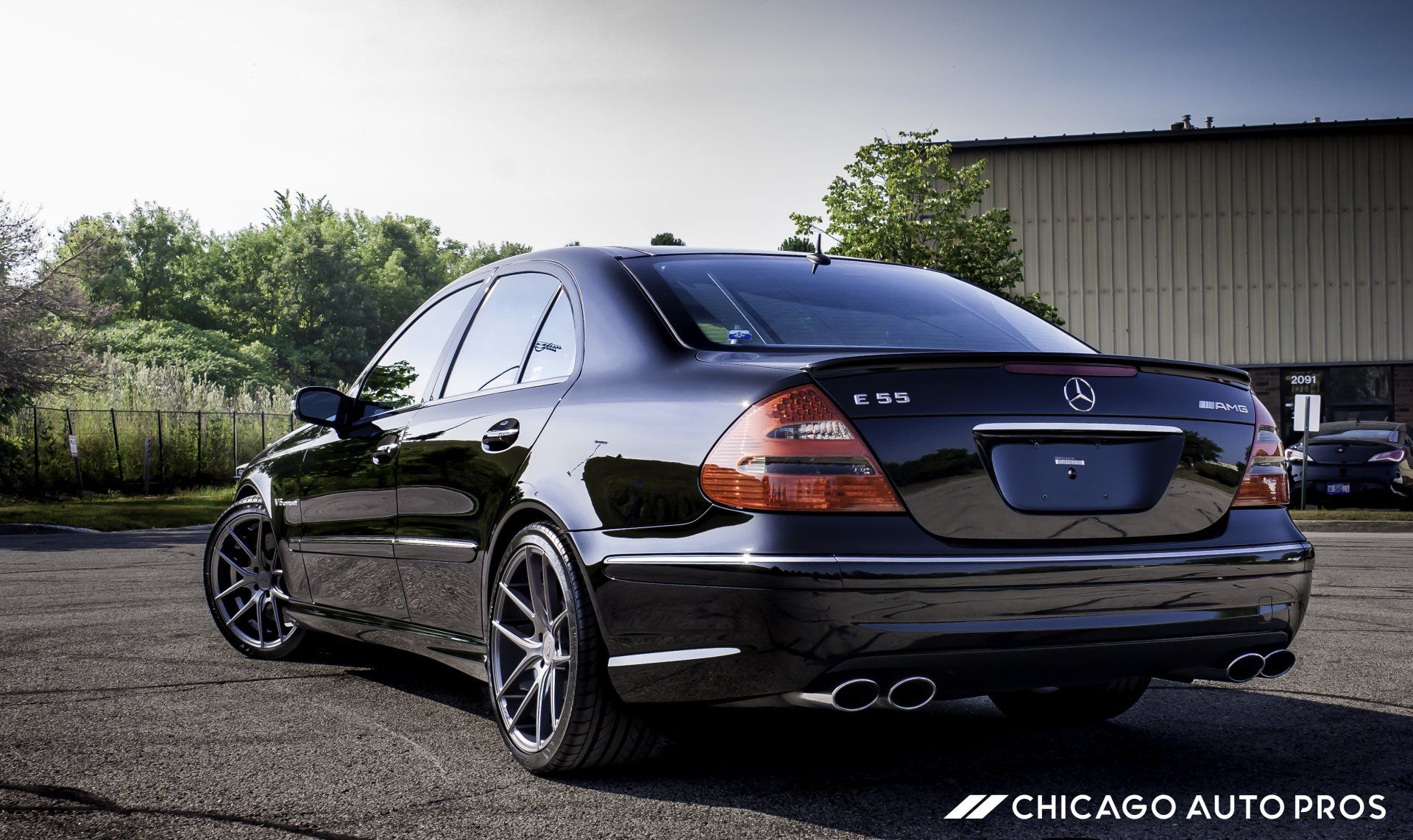 A black mercedes benz is parked in front of a building.