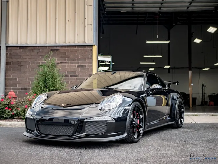 A black porsche 911 gt3 rs is parked in front of a brick building.