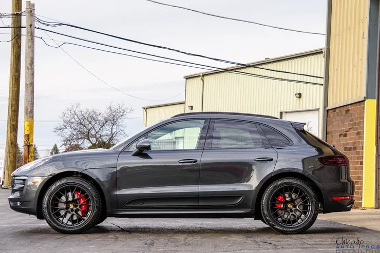 A black porsche macan turbo is parked in front of a building.
