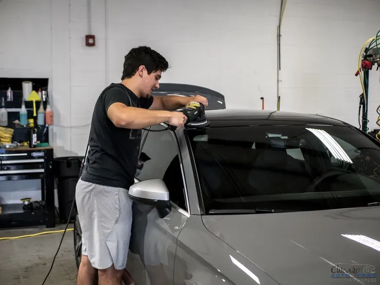 A man is polishing a car in a garage.