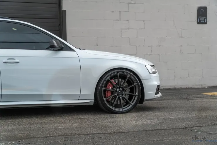 A white audi a4 is parked in a parking lot in front of a building.