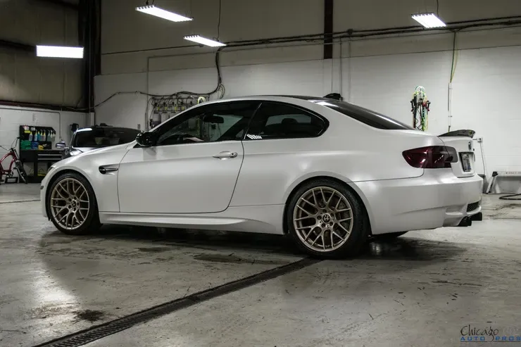 A white bmw m3 is parked in a garage.