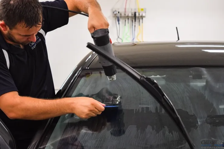 A man is applying tinted glass to a car window.
