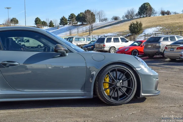 A gray porsche 911 gt3 is parked in a parking lot.
