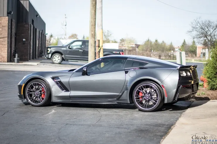 A gray corvette zr1 is parked in a parking lot next to a building.