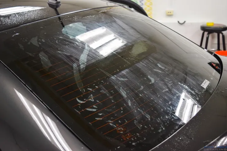 A car with a dirty windshield is sitting in a garage.
