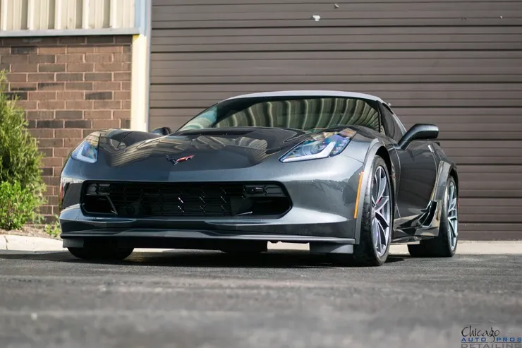 A gray sports car is parked in front of a brick building.