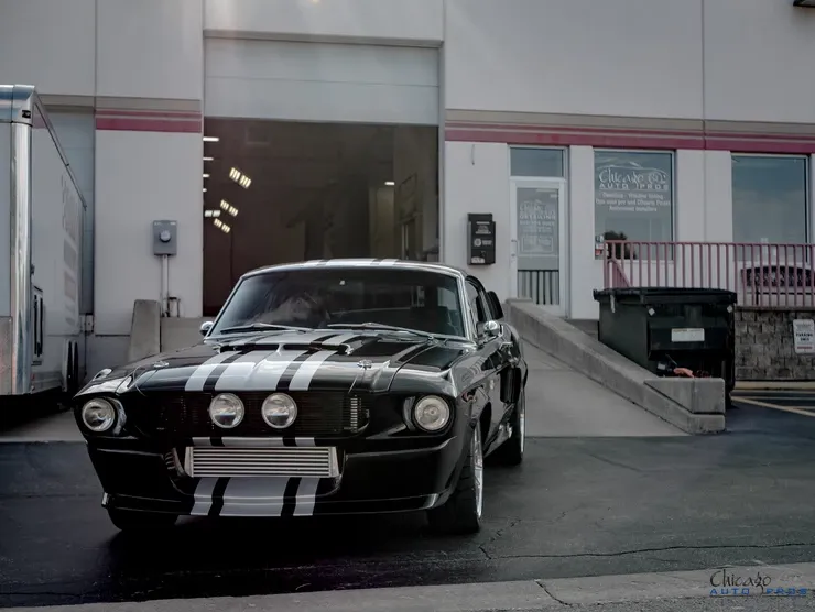 A black mustang is parked in front of a building