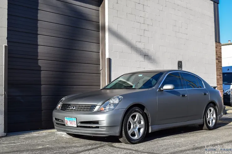 A silver car is parked in front of a garage door.