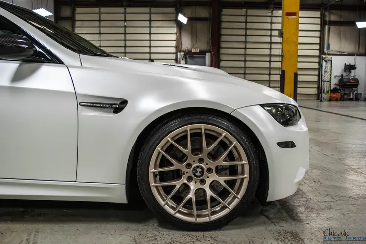A white bmw m3 is parked in a garage.