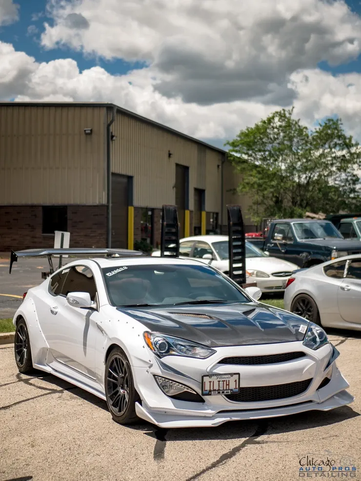A white car is parked in front of a building.