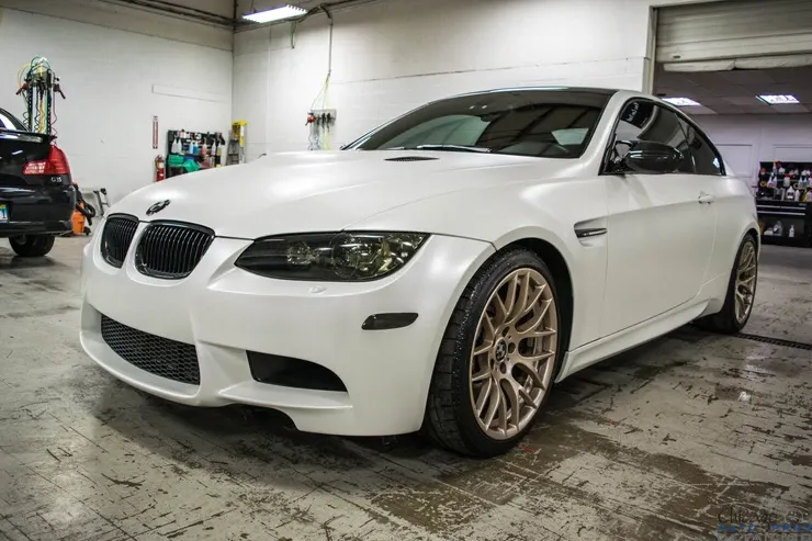 A white bmw m3 is parked in a garage.