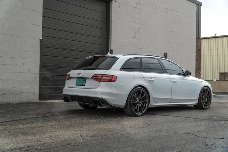 A white audi a4 is parked in front of a garage door.