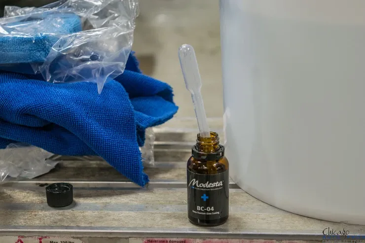 A bottle of liquid with a pipette in it is sitting on a table next to a blue towel.